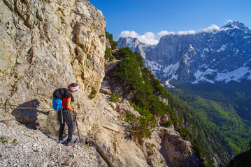 Young woman with backpack hiking along the path in the scenic Julian Alps, Italy, Europe