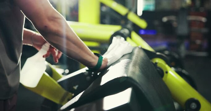 Gym, hands and spray for cleaning equipment, safety or hygiene for maintenance. Man, health or wipe fitness machine with cloth at sports club for disinfection, sanitation and remove bacteria or virus