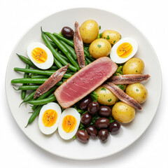 Ni&ccedil;oise salad with seared tuna, green beans, potatoes, eggs, olives and anchovies, beautifully arranged on a white plate isolated on white