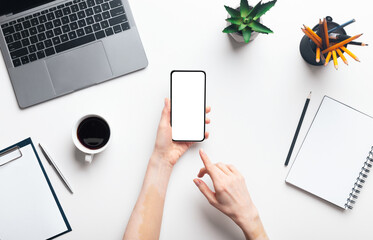 Woman hands using cellphone in office while working, copy space, top view, blank screen