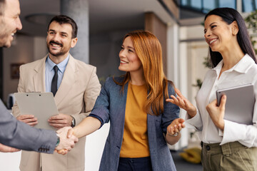 Friendly female leader is shaking hands with business partner at corporate office.