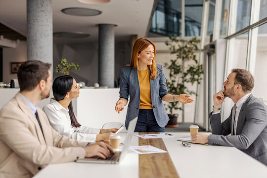 Female executive standing at boardroom and having meeting with her team of experts.
