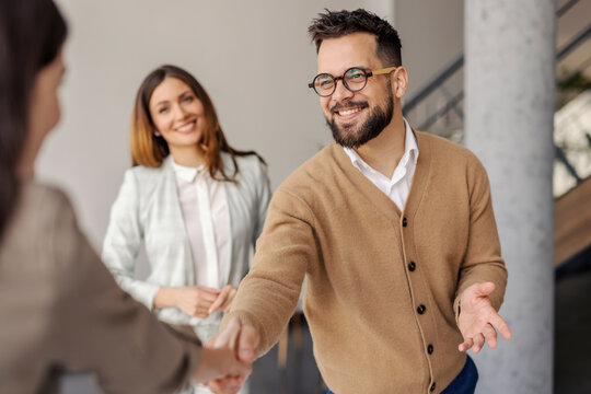 Portrait of friendly businessman standing at corporate office and shaking hands with his business partner.