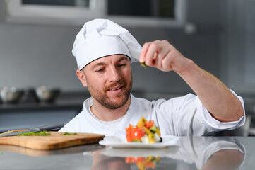 food cooking, profession and people concept - happy male chef cook with plate of salad at restaurant kitchen table
