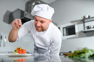 food cooking, profession and people concept - happy male chef cook with plate of salad at restaurant kitchen table