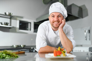Portrait of happy caucasian male chef standing in restaurant kitchen, copy space