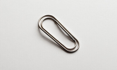 A single metal paperclip lying on a clean white surface