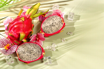 Dragon fruit, pitaya on a sunny table with shadows from a palm tree and orchid flowers, advertising...