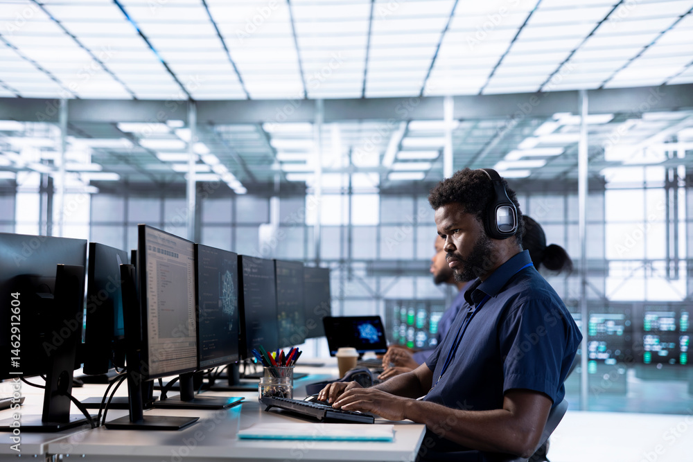 Poster engineer in data center listening music while using pc to check for server performance issues arisin