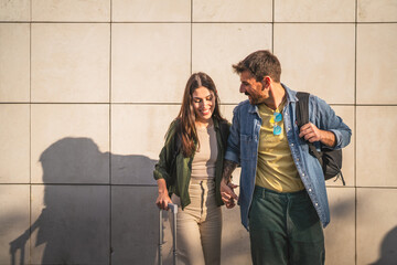 Fototapeta premium Portrait of couple stand with suitcase in front white wall
