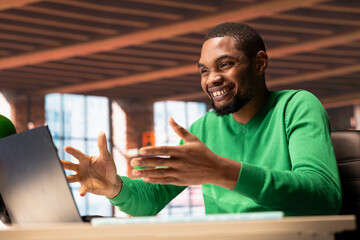 Happy man reading good news on laptop screen at home and cheering. Delighted african american...