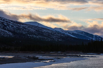 Snowy mountains glow softly at sunset in Alaska.
