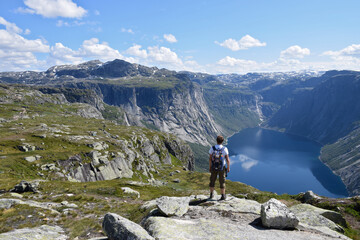 Norway. Amazing nature view on the way to Trolltunga. Hiker man staying on a cliff over a lake. Travel concept.