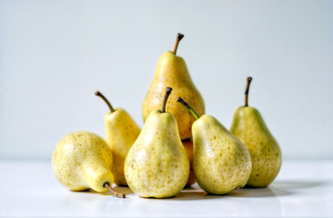 Seven yellow pears at varying ripeness on white background. Simple fresh fruit still life with natural lighting.