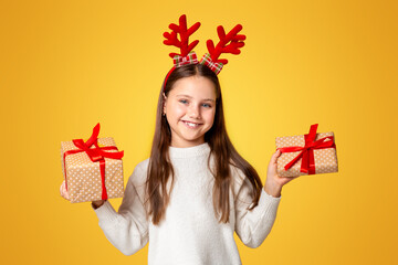 Childhood, Christmas and mood. Smiling kid with horns and in sweater holding two gifts in her hands...