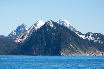 Obraz premium Snow capped mountains rise dramatically on the Kenai Peninsula, off the Alaskan coast.
