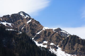 Snow capped mountains rise dramatically on the Kenai Peninsula, off the Alaskan coast.