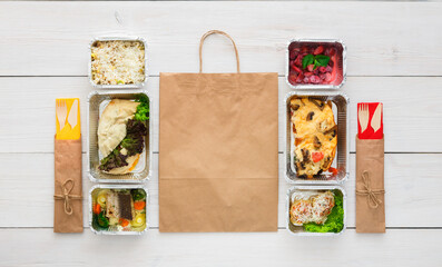 Obraz premium Healthy food delivery. Take away of natural organic fitness dishes for diet. Daily ratio meals in foil boxes on white wood. Craft package, vegetables, meat and salads. Top view, flat lay