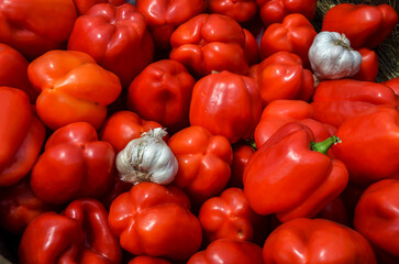 Fresh red bell peppers with garlic bulbs, showcasing produce in a vibrant arrangement. The vivid colors convey freshness, ideal for culinary or agricultural contexts