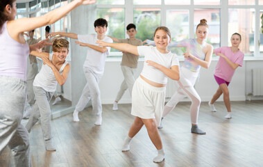 Naklejka premium Young girls and boys repeat the movements of dance teacher, training in a spacious studio