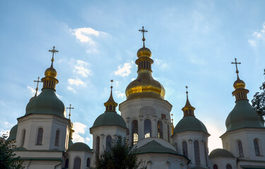Golden domes of Saint Sophia Cathedral in Kyiv, Ukraine, against a clear blue sky. The architectural details and vibrant colors are prominently featured