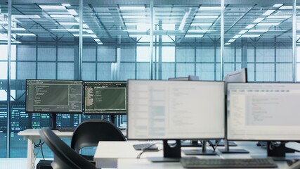 Code running on computer screens in empty data center workspace, used for troubleshooting rackmounts. Close up of script working on desktop PC monitors upgrading mainframes systems in server room