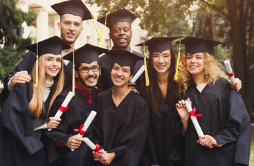 Multiethnic students taking group photo to celebrate their graduation day, copy space. Education,...