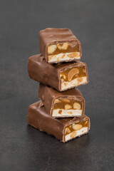 Chocolate bar. Nougat, caramel with peanuts, in milk chocolate. Dark gray background