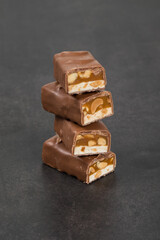 Mini Chocolate bar. Nougat, caramel with peanuts, in milk chocolate. Dark gray background