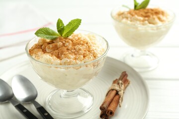 Delicious rice pudding with cinnamon and mint on table, closeup