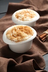 Delicious rice pudding with cinnamon in bowls on table, closeup