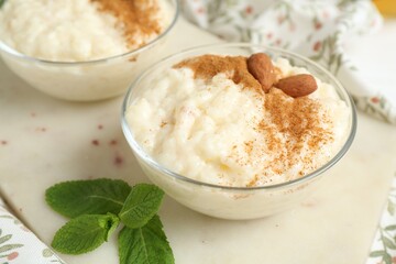 Delicious rice pudding with cinnamon, almonds and mint on table, closeup