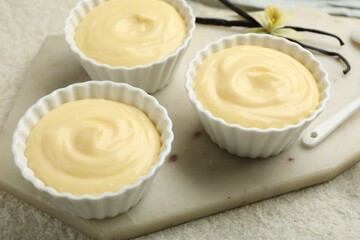 Tasty vanilla pudding with pods and flower on light textured table, closeup