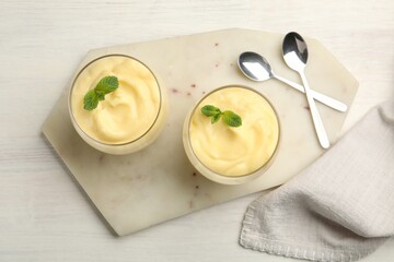 Tasty vanilla pudding with mint served on white wooden table, flat lay