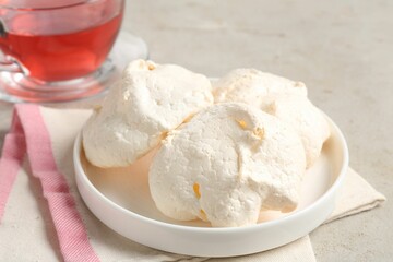 Delicious homemade meringue cookies and tea on gray table, closeup