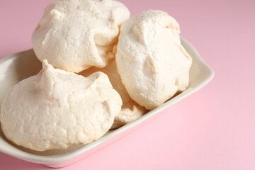 Delicious homemade meringue cookies in bowl on pink background, closeup