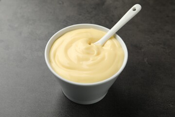 Tasty vanilla pudding with spoon on black table, closeup