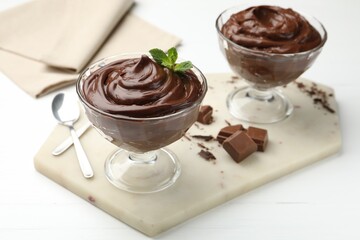 Delicious chocolate pudding in dessert bowls on white wooden table, closeup