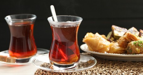 Traditional Turkish tea in glass cups and sweets on white table, closeup