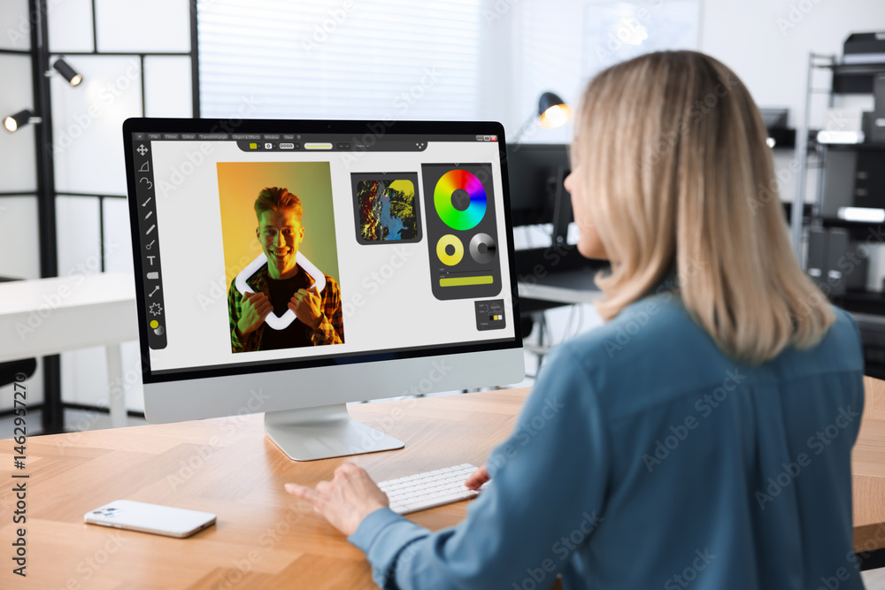 Poster designer working on computer at table in office