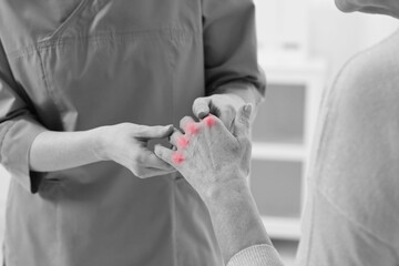 Arthritis. Doctor examining patient's hand in hospital, closeup. Black and white toning with red...