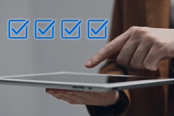 Approved. Woman using tablet on grey background, closeup. Check marks above device