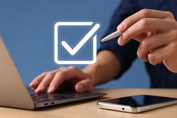 Approved. Man using laptop and touching virtual screen with check mark at table, closeup