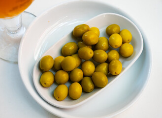 Appetites are waiting on table, light snack - bowl with pickled green olives and garlic, complemented by glass of beer