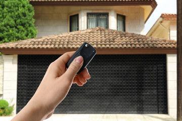 Woman using remote to control garage door outdoors, closeup