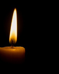 A single lit candle burning softly in the dark. 