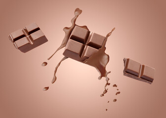 Chocolate pieces and splash of cocoa drink in air on pale brown gradient background