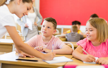 Interested preteen pupils divided into small groups, discussing learning material in classroom. Group work as effective teaching method