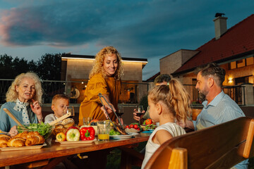 Family enjoying barbecue dinner on patio in the evening