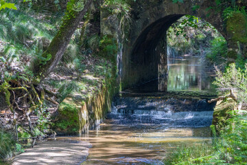 Water flowing under old stone bridge in tapada nacional de mafra, portugal